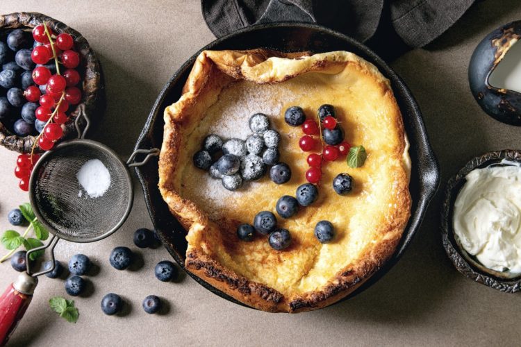 Dutch baby with berries in a seasoned cast iron pan