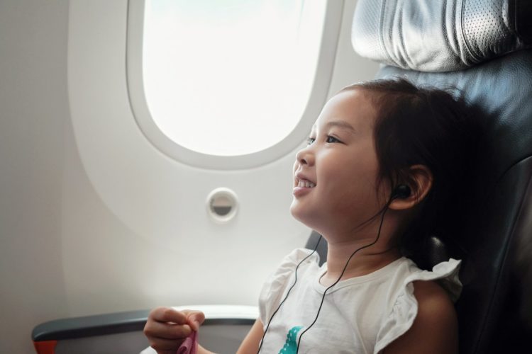 Little girl flying on a plane listening to music