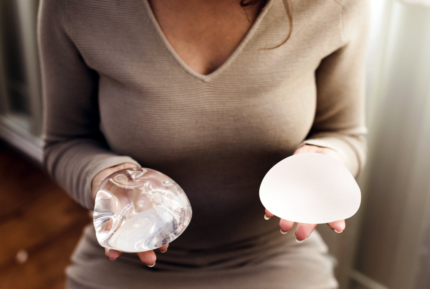 Woman holding silicone breast implants for plastic surgery