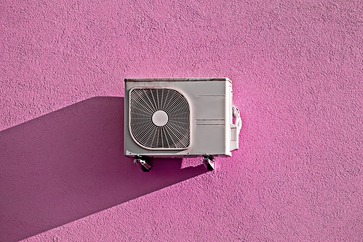 Air conditioning unit on pink stucco