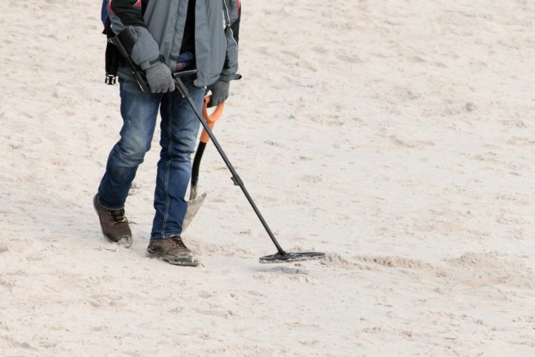 Man walking the beach with a metal detector