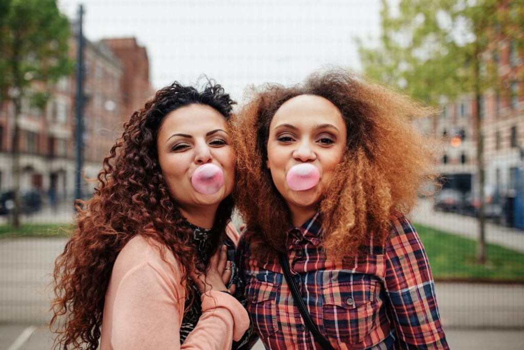 Women blowing bubbles with chewing gum